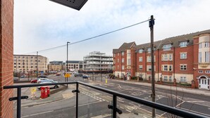 A street view with a building under construction, a red brick building with multiple windows, and a clear sky. - Modern & Stylish 2 Bed York Apartment (York)