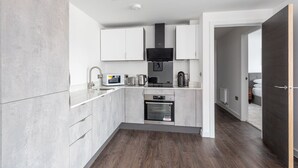 A modern kitchen with white cabinetry, a built-in microwave, a coffee maker, and a toaster. - Modern & Stylish 2 Bed York Apartment (York)