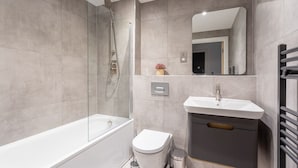 A modern bathroom with a glass-enclosed shower, a white bathtub, a toilet, and a vanity with a mirror. - Modern & Stylish 2 Bed York Apartment (York)
