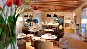 A modern hotel lobby with round tables, comfortable seating, and a warm wooden ceiling.