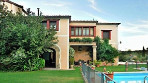 A two-story building with a swimming pool, surrounded by greenery and a well-maintained lawn.
