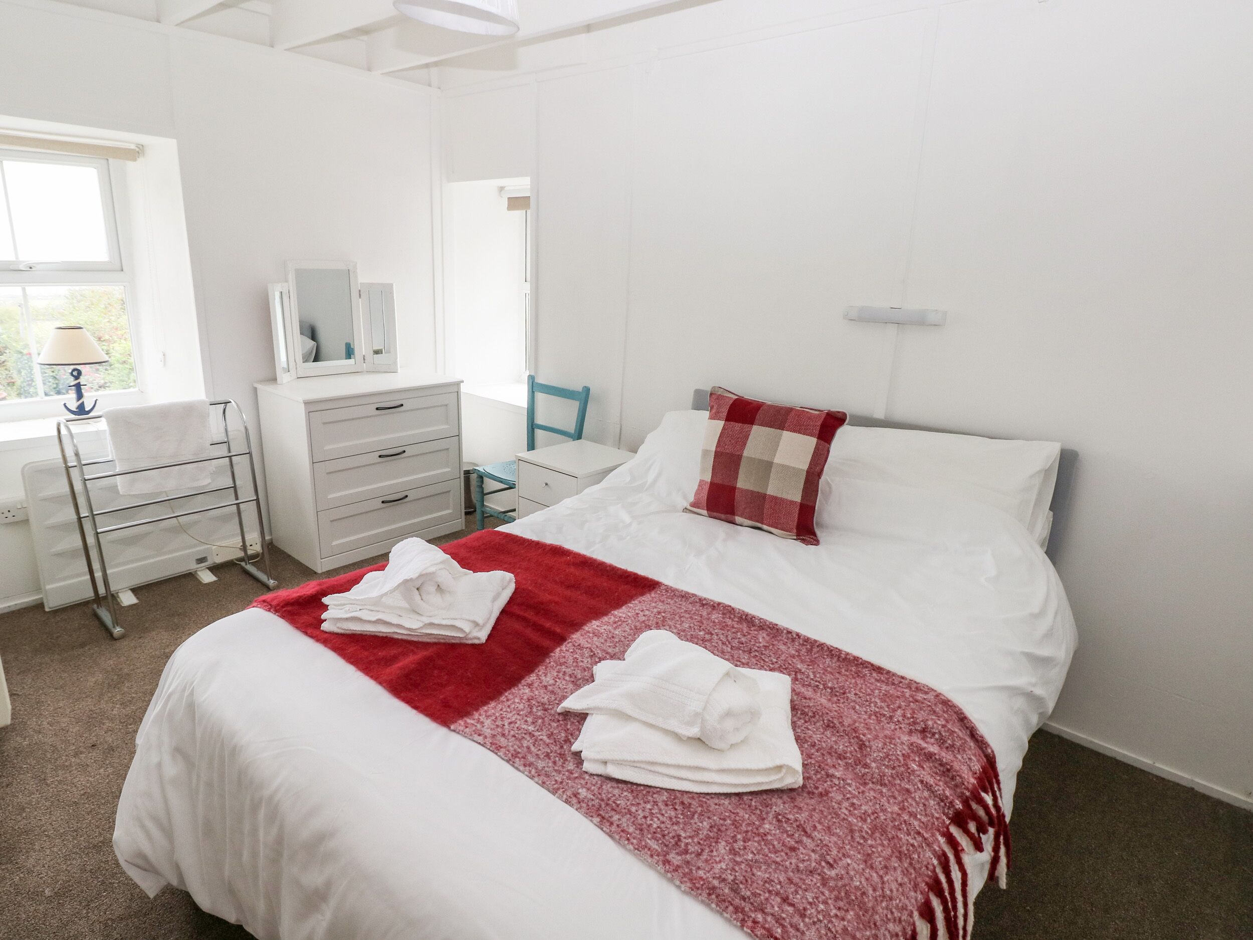 A neatly arranged bedroom with a bed, a desk, and a chair.