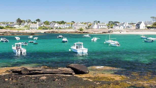 A coastal village with boats docked in clear waters, surrounded by white houses and a rocky shoreline. - Roulotte Karantez Hébergement Insolite à 800 m des Plages Séjour 100 % Cocooning (Porspoder)