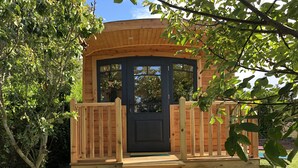 A wooden cabin with a dark door, a wooden deck, and a set of stairs leading to the entrance. - Roulotte Karantez Hébergement Insolite à 800 m des Plages Séjour 100 % Cocooning (Porspoder)