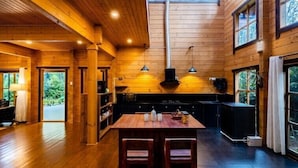 A spacious wooden interior with a high ceiling, large windows, and a central dining area.
