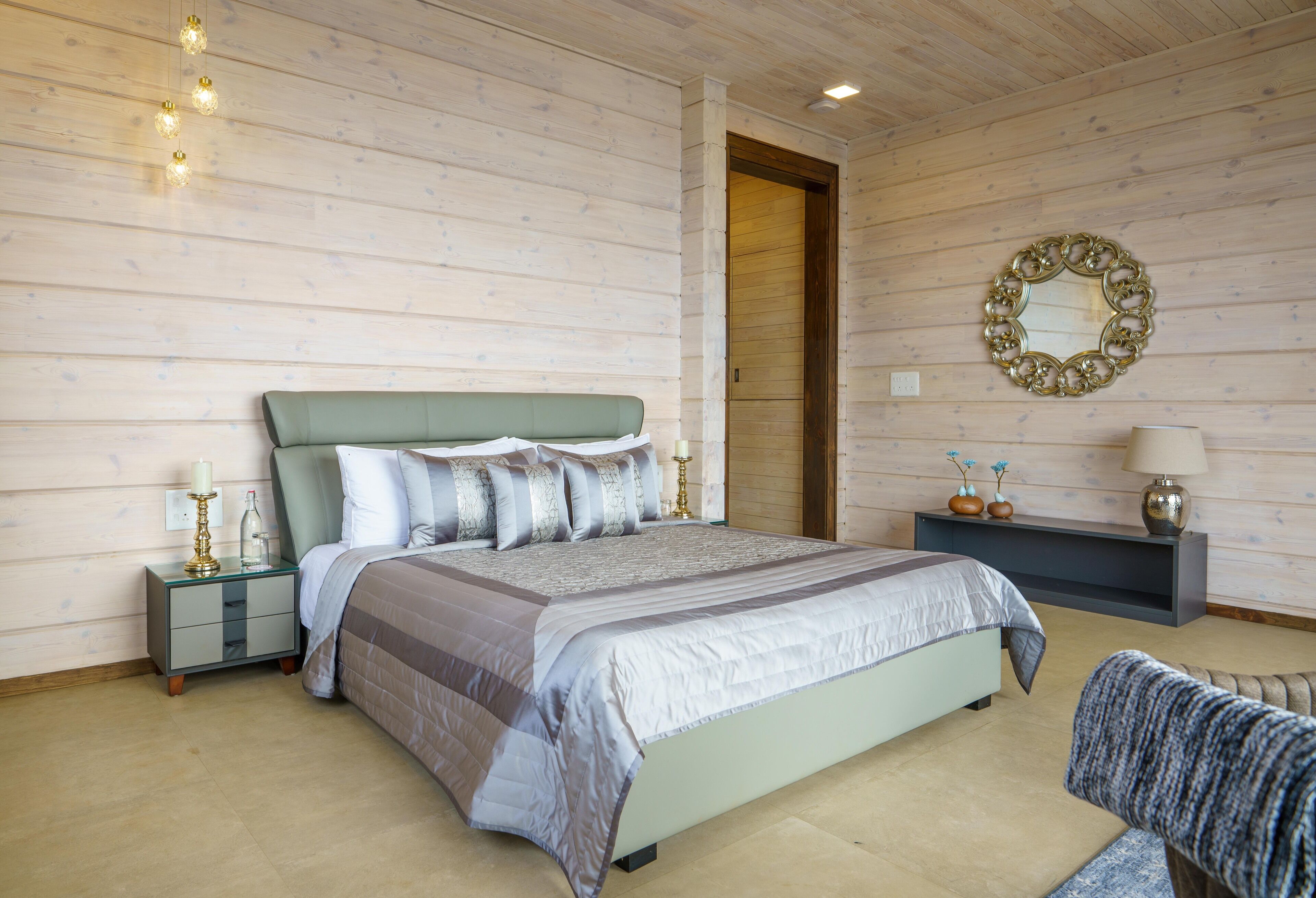 Une chambre à coucher avec un lit, des tables de chevet, un miroir et un banc.