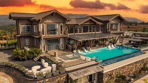 Une grande maison moderne dotée d’une piscine, de plusieurs terrasses et offrant une vue imprenable sur les montagnes.