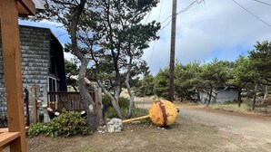 A rustic outdoor area with a wooden deck, a stone building, and a large wooden wheel. - The Chillton Cozy cabin steps to beach (Cloverdale)