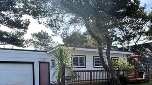 A single-story mobile home with a fenced backyard, a garage, and a small tree. - The Chillton Cozy cabin steps to beach (Cloverdale)