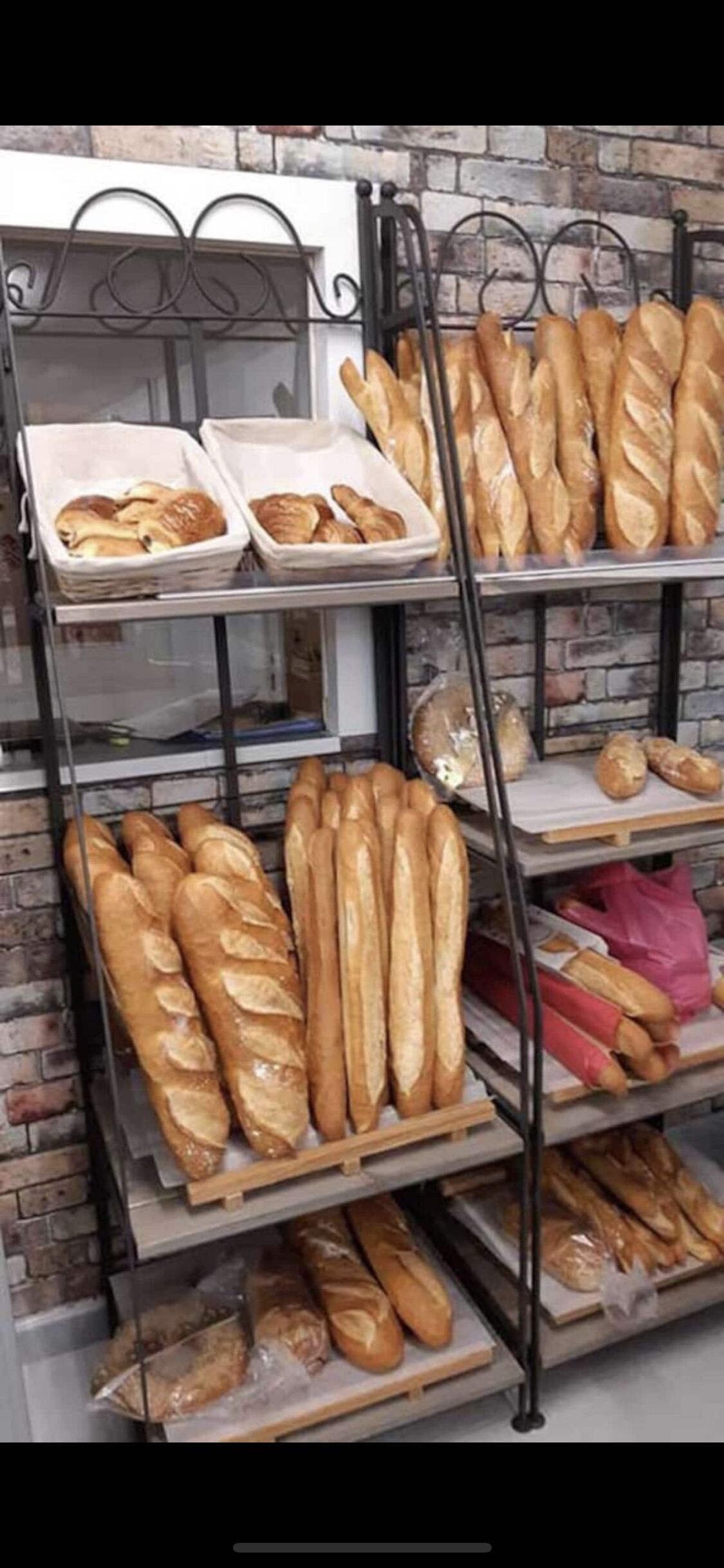 Une vitrine de boulangerie présentant différents types de pain sur des étagères en métal.