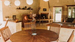 Ein rustikales Interieur mit einem runden Holztisch, Holzstühlen, einem Kamin und einer Steinwand.
