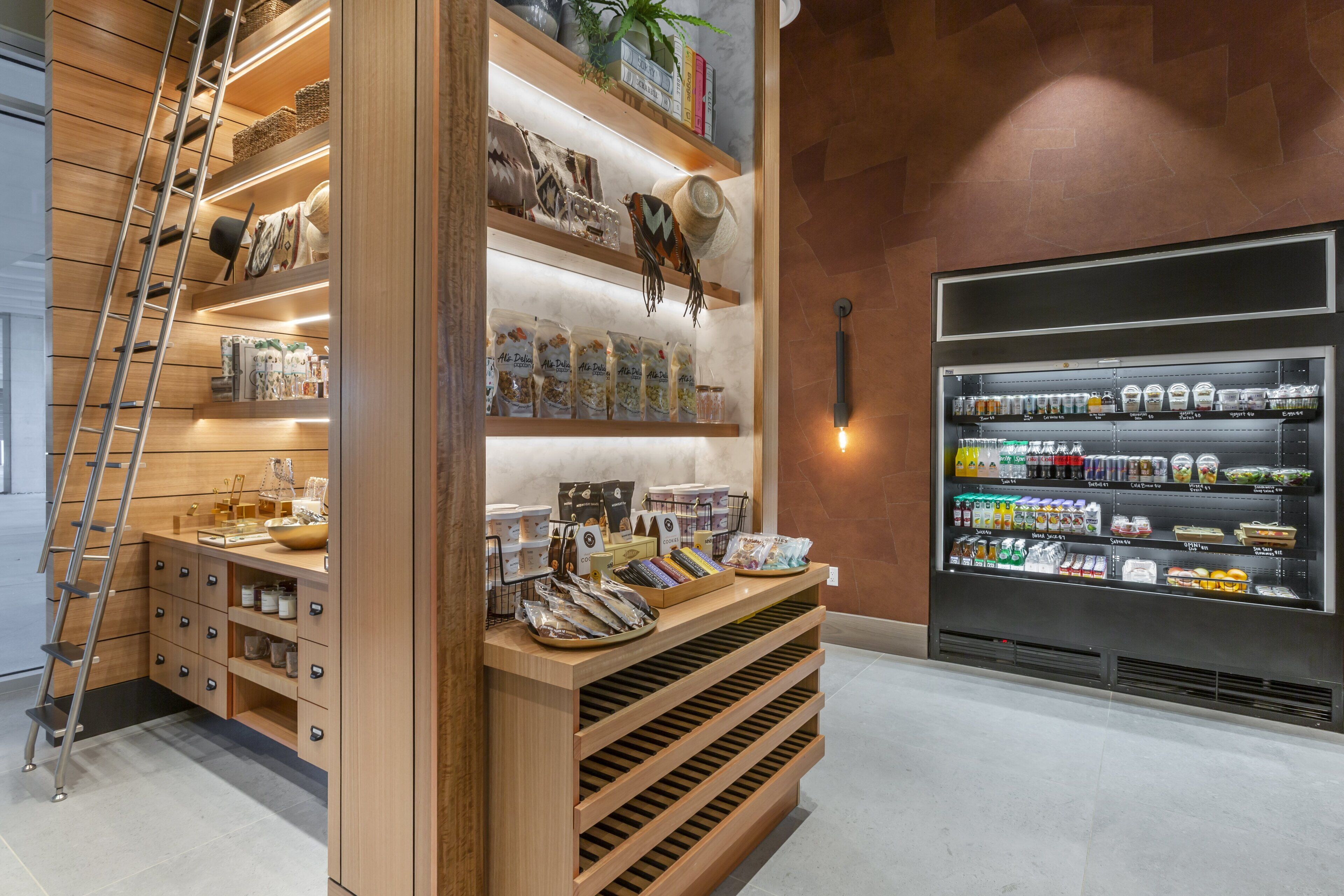 A modern retail space with wooden shelving, a ladder, and a refrigerated display.