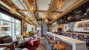 A modern bar area with wooden beams, bar stools, and a long counter. - Omni Tempe Hotel at ASU (Tempe)