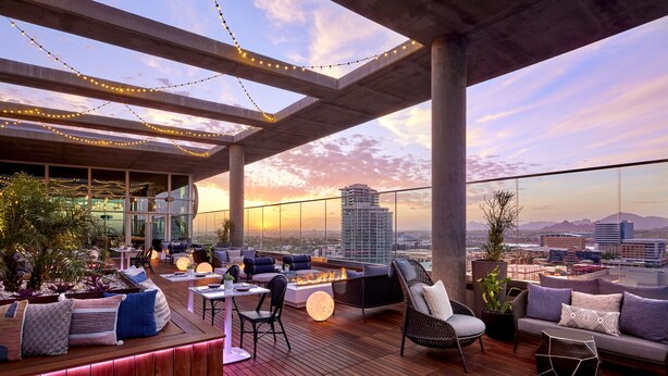 A rooftop terrace with outdoor seating, a fire pit, and a city view at sunset. - Omni Tempe Hotel at ASU (Tempe)