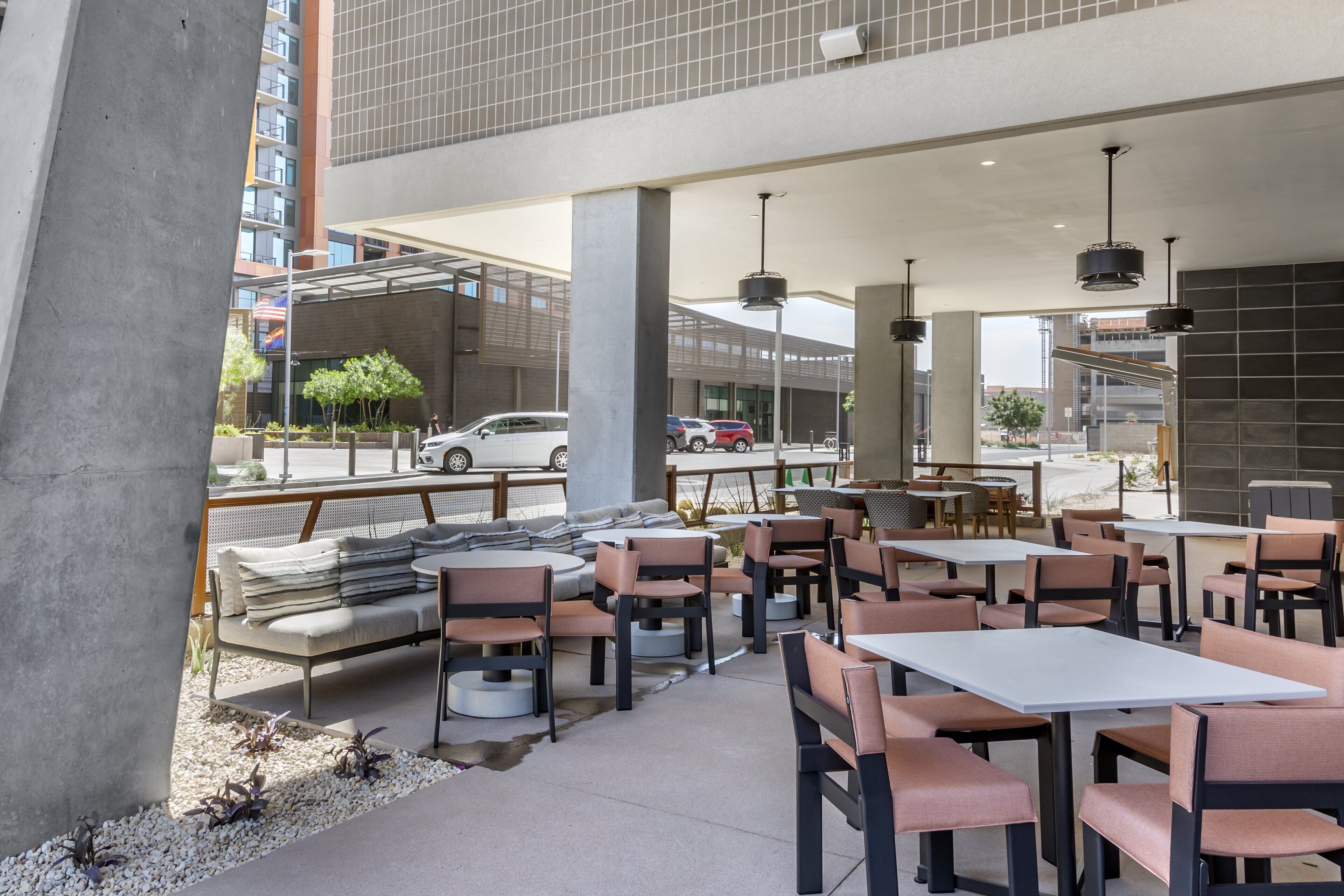 An outdoor cafe with tables and chairs, a concrete pillar, and a view of the street.