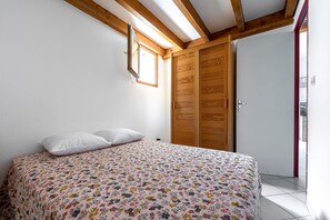 Une chambre à coucher avec un lit, une armoire en bois et une fenêtre.