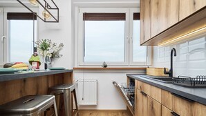 Une cuisine moderne avec des meubles en bois, un robinet noir et une fenêtre équipée de stores.