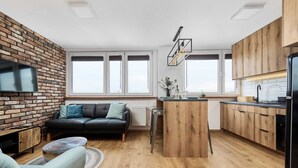 Une cuisine moderne avec des meubles en bois, un îlot central intégré et un réfrigérateur noir.