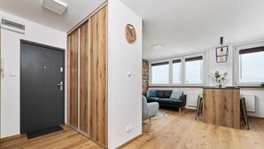 Un espace de vie moderne avec un plancher en bois, une porte sombre, un canapé, une table basse et une fenêtre donnant sur un beau paysage.