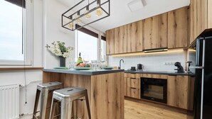 Une cuisine moderne avec des meubles en bois, un îlot central, des tabourets de bar et un four encastré.