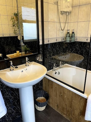 A bathroom with a sink, mirror, and bathtub. There is a wooden panel wall and a tiled floor. - Captivating House in Bangor, Northern Ireland (Bangor)