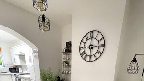 Eine moderne Küche mit weißen Schränken, einem eingebauten Backofen und einem Essbereich mit einem Glastisch und Metallstühlen.