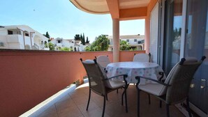 A balcony with a table and chairs, a sliding glass door, and a view of neighboring houses.