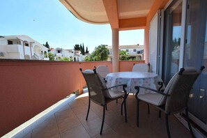 A balcony with a table and chairs, a sliding glass door, and a view of neighboring houses. - Holiday apartment mit Klimaanlage und Balkon (Malinska)