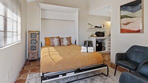 A bedroom with a bed, a chair, a desk, and a painting. - Lakefront Escape | Pool • Spa • 4 Min to Downtown (Chandler)