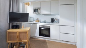 Uma cozinha moderna com forno embutido, micro-ondas e uma TV de tela plana sobre uma mesa de madeira.