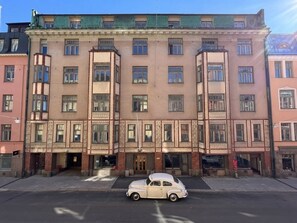 A multi-story building with a central entrance, a car parked in front, and a clear sky. - Luotsi 1911 Suites (Helsinki)