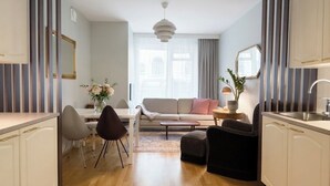 Una sala de estar moderna con sofá, mesa de comedor, sillas y una cocina con armarios y fregadero.