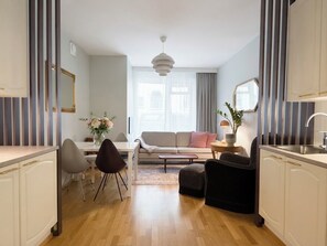Ein modernes Wohnzimmer mit einer Couch, einem Esstisch, Stühlen und einer Küchenzeile mit Schränken und einer Spüle.