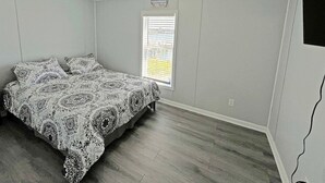 Une chambre à coucher avec un lit, une fenêtre avec des stores et un luminaire au plafond.