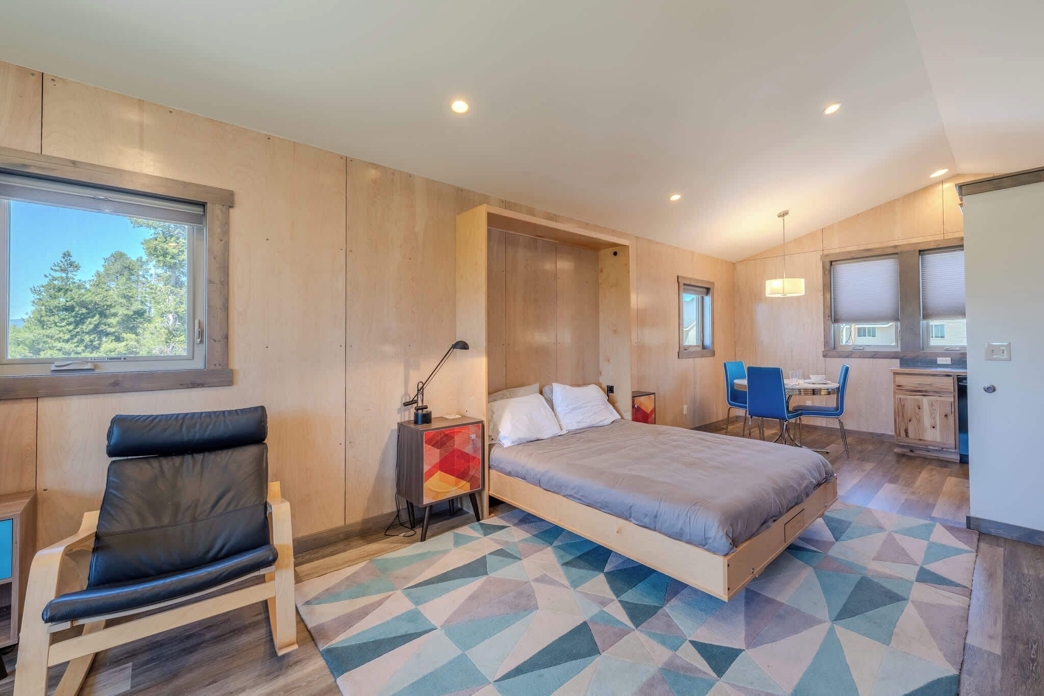 Een moderne slaapkamer met een bed, een stoel, een bureau en een raam.