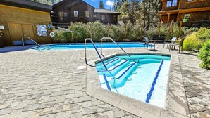 A pool area with a brick deck, a diving sign, and two wooden cabins in the background. - One Bedroom plus Loft River View Condo (Alpine Meadows)