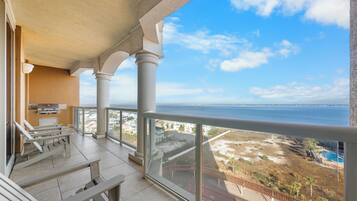 A balcony with a view of the sea, a pool, and a beach.