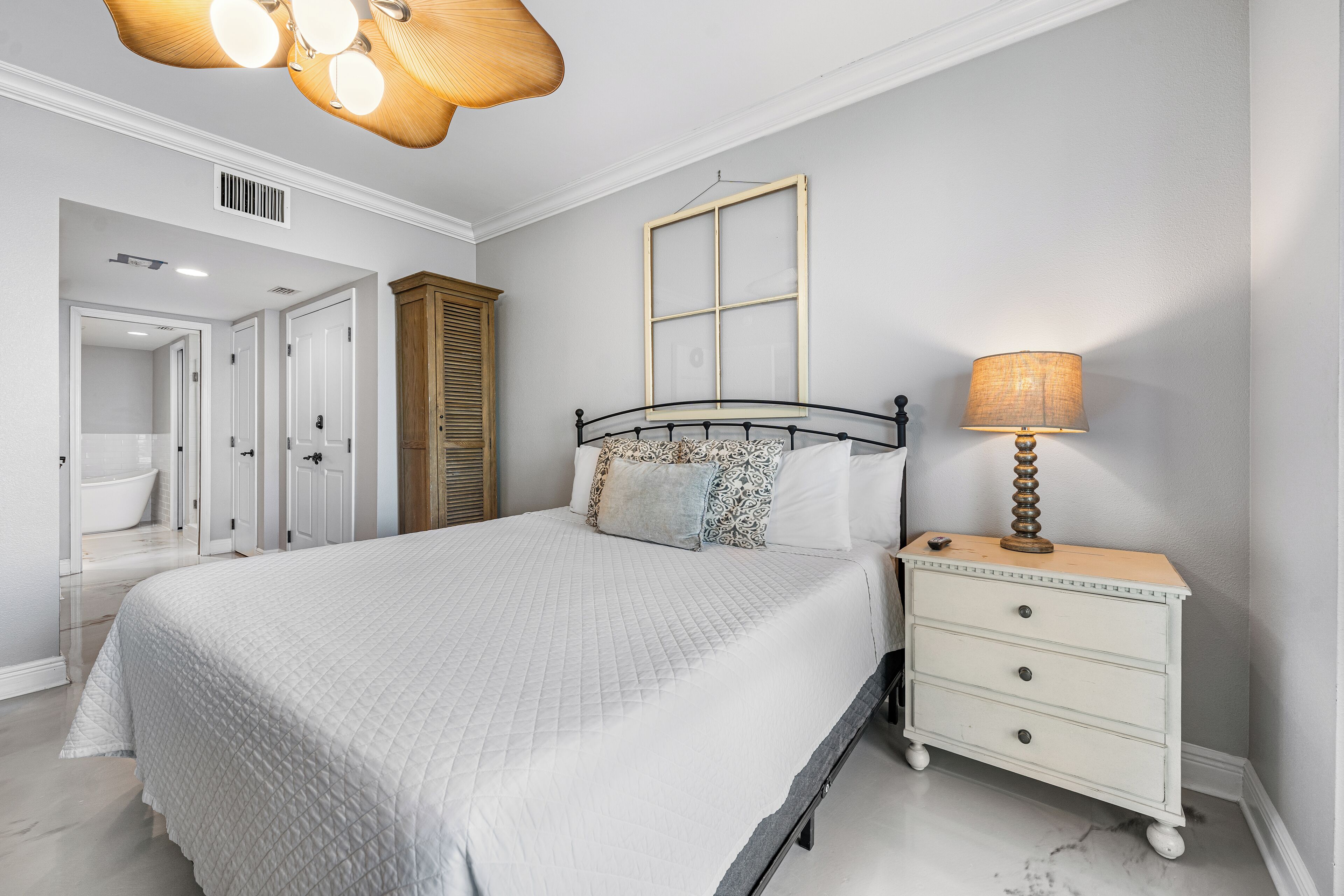 Un dormitorio con cama, mesita de noche, lámpara y ventana.