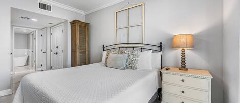 Un dormitorio con cama, mesita de noche, lámpara y ventana.