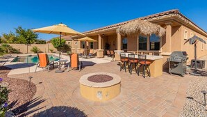An outdoor patio area with a pool, lounge chairs, a barbecue grill, and a fire pit. - Luxury Stay at Estrella Mountain Ranch (Goodyear)