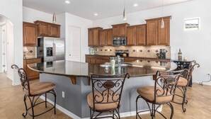 A modern kitchen with a large island, stainless steel appliances, and wooden cabinets. - Luxury Stay at Estrella Mountain Ranch (Goodyear)