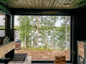 A cabin with a large window overlooking a forest and a lake.