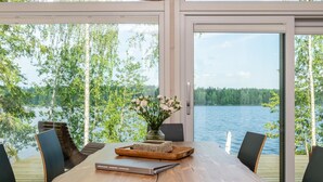 A dining area with a wooden table, chairs, and a vase of flowers. - Hot pool cottage kesäranta by Interhome (Enonkoski)