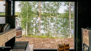 A cabin with a large window overlooking a forest and a lake. - Hot pool cottage kesäranta by Interhome (Enonkoski)