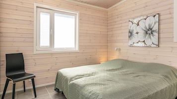 A room with a bed, a chair, a window, and a wall-mounted artwork.