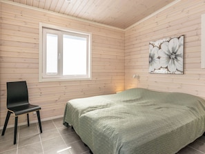 A room with a bed, a chair, a window, and a wall-mounted artwork.