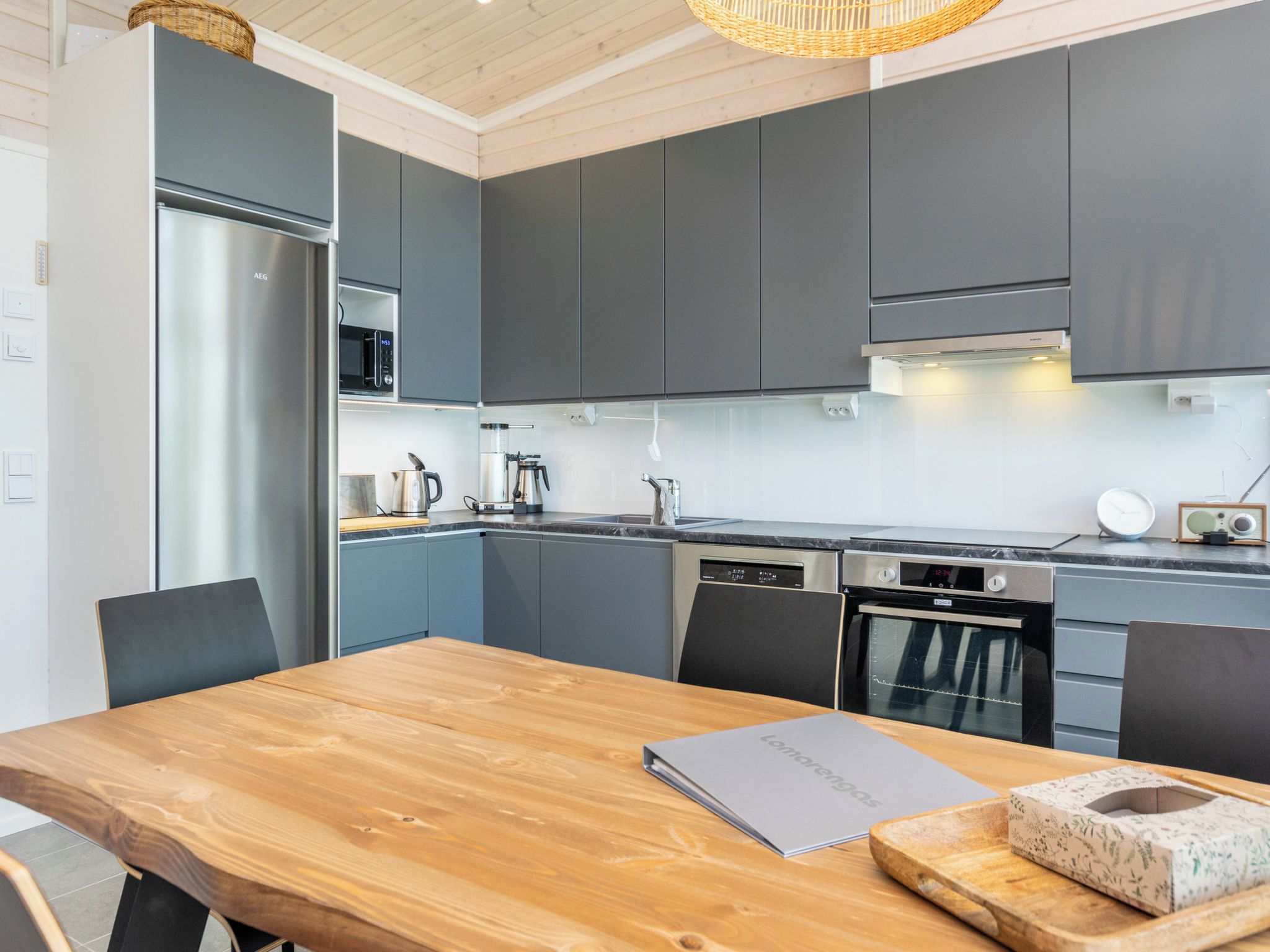 Una cocina moderna con armarios grises, electrodomésticos de acero inoxidable y una mesa de comedor de madera.
