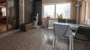 Ein modernes Interieur mit Kamin aus Stein, einem Essbereich mit Glastisch und Blick ins Freie durch große Fenster.