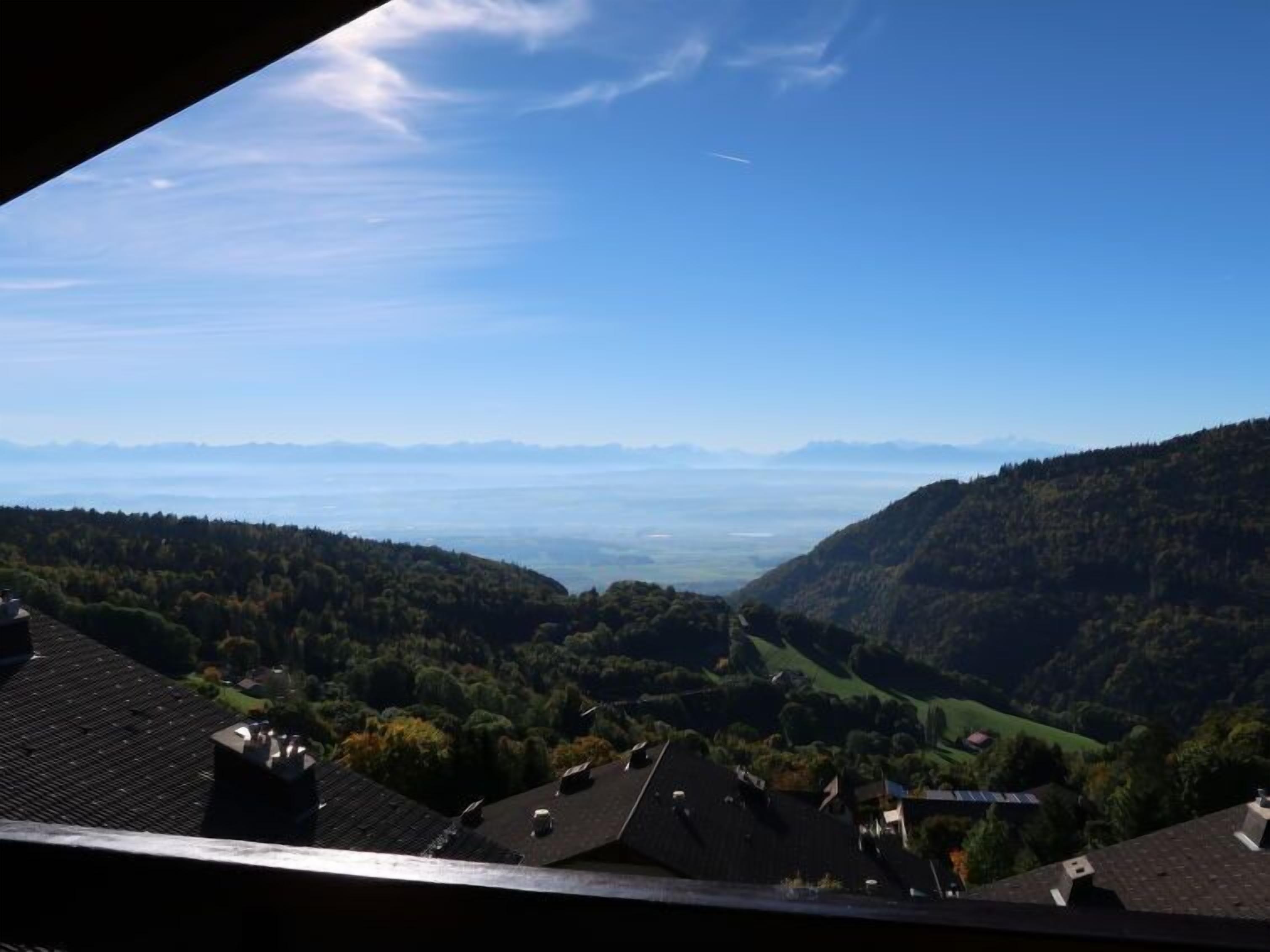 A view from a window overlooking a valley with houses and a clear sky.