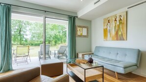 En moderne stue med et glasbord, en lyseblå sofa og udsigt til en have gennem store skydedøre.